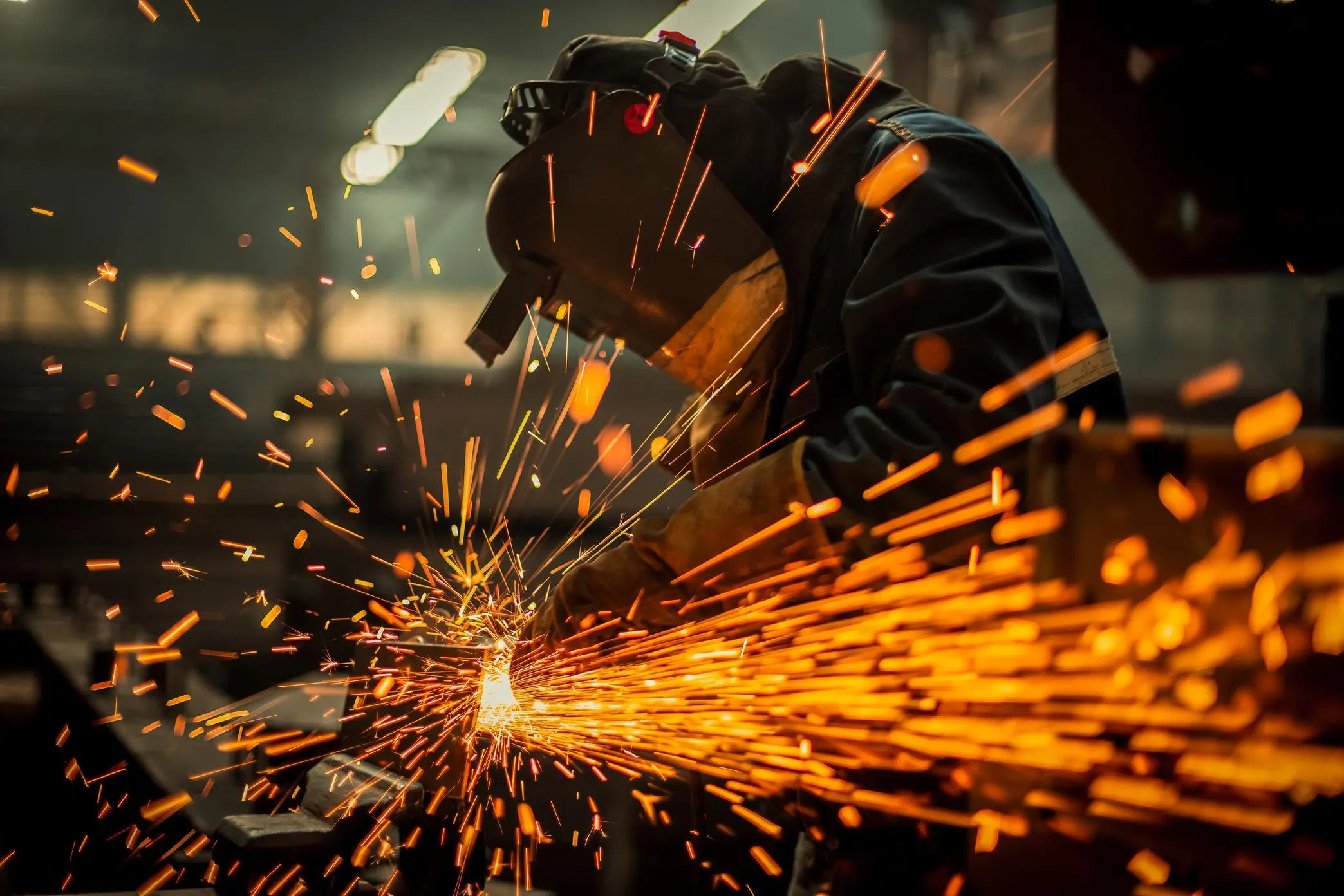 Profissional cortando ferro em metalúrgica, faíscas de corte